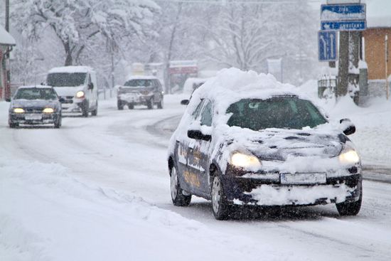 Henkilöautoja ajaa lumisella tiellä